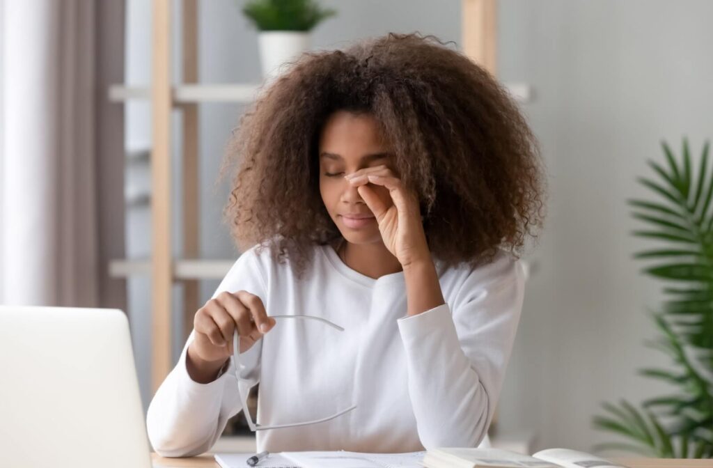 Person rubbing their eyes from irritation, while working on computer.