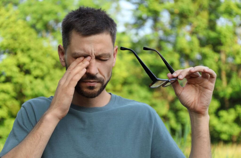 A person removes their glasses to try and soothe their irritated eyes.