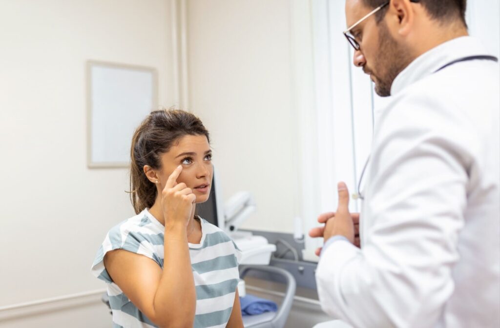 A patient points to their eye while talking to their optometrist about their dry eye symptoms.